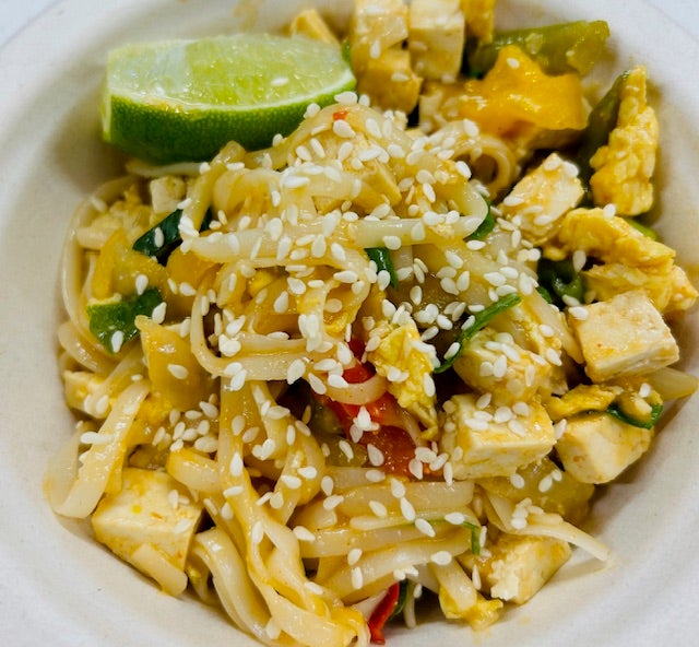 Heaping pile of Tofu Pad Thai with vegetables, topped with sesame seeds and with a lime wedge on the side